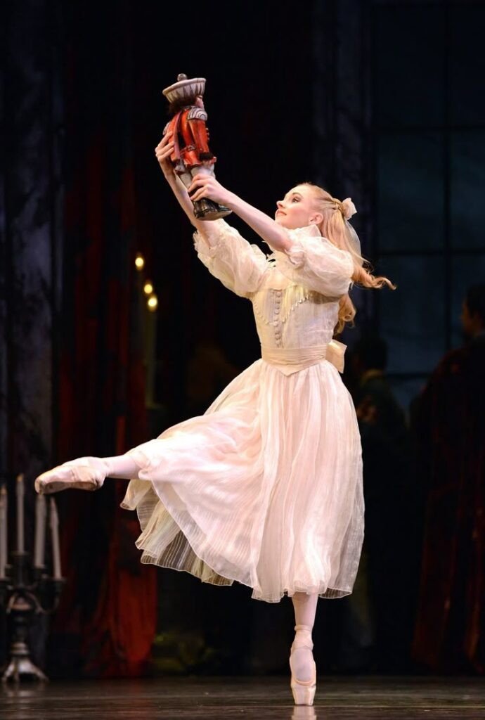 Birmingham Royal Ballets The Nutcracker Ballet dancer in white costume performs on stage holding a nutcracker, evoking a classic Nutcracker ballet scene. | Sky Rye Design Ballet dancer in white costume performs on stage holding a nutcracker, evoking a classic Nutcracker ballet scene.