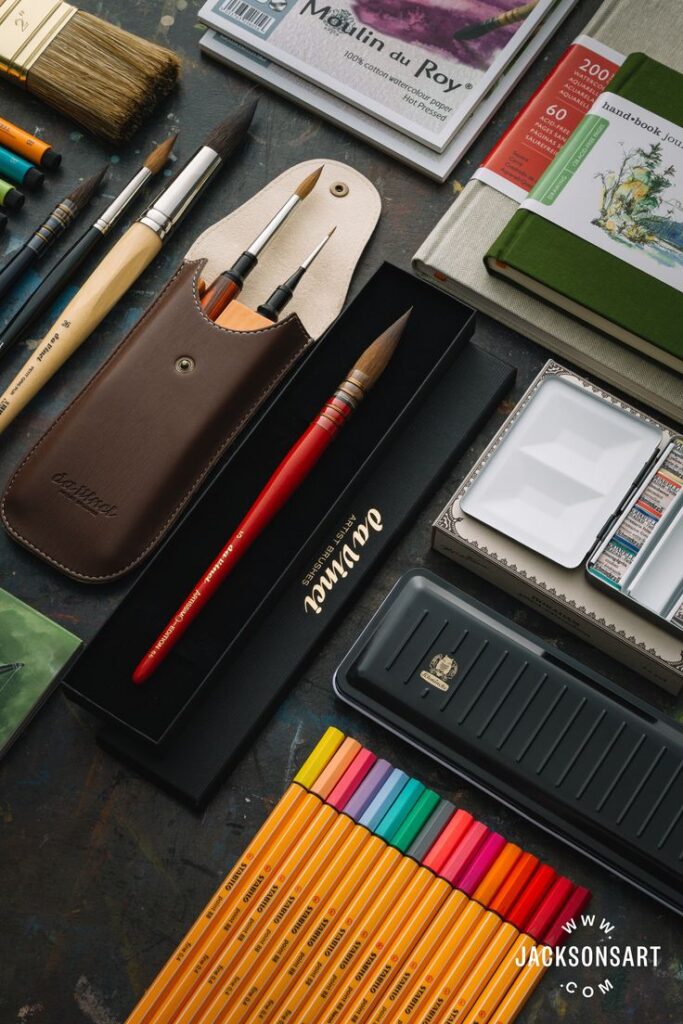 Black Friday Deals Art supplies including brushes, paints, sketchbooks, and colored pencils arranged creatively on a table for artistic inspiration. | Sky Rye Design Art supplies including brushes, paints, sketchbooks, and colored pencils arranged creatively on a table for artistic inspiration.