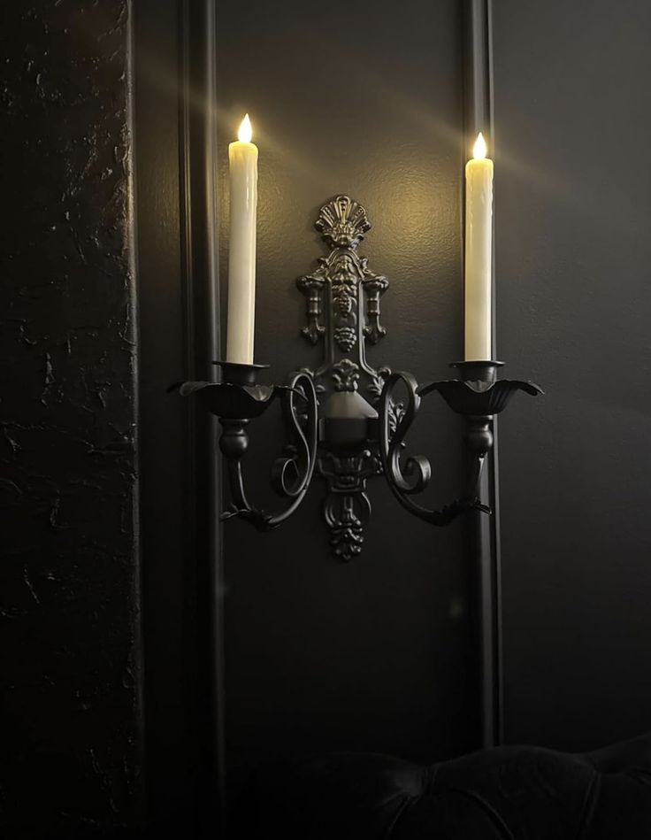 Screenshot Elegant black wall sconce with two lit candles on a dark textured background, creating a warm and classic ambiance. | Sky Rye Design Elegant black wall sconce with two lit candles on a dark textured background, creating a warm and classic ambiance.
