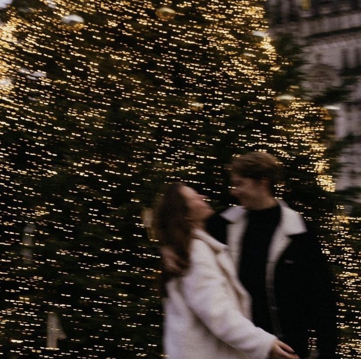 Screenshot Couple enjoying a festive moment in front of a beautifully lit Christmas tree adorned with sparkling lights and baubles. | Sky Rye Design Couple enjoying a festive moment in front of a beautifully lit Christmas tree adorned with sparkling lights and baubles.