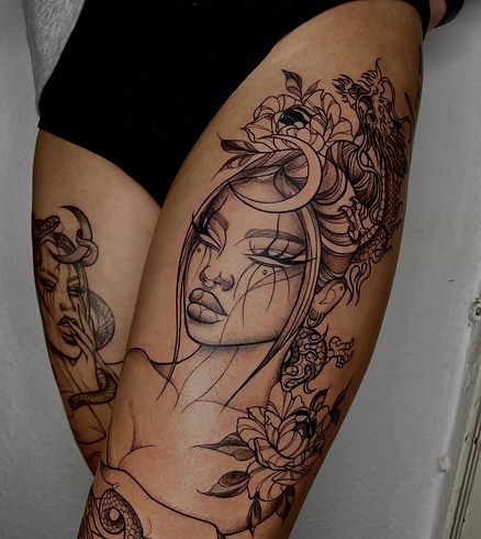 Book a tattoo _ Ruby Rose Designs Thigh tattoo art featuring an intricate portrait of a woman with flowers and celestial elements in black ink. | Sky Rye Design Thigh tattoo art featuring an intricate portrait of a woman with flowers and celestial elements in black ink.