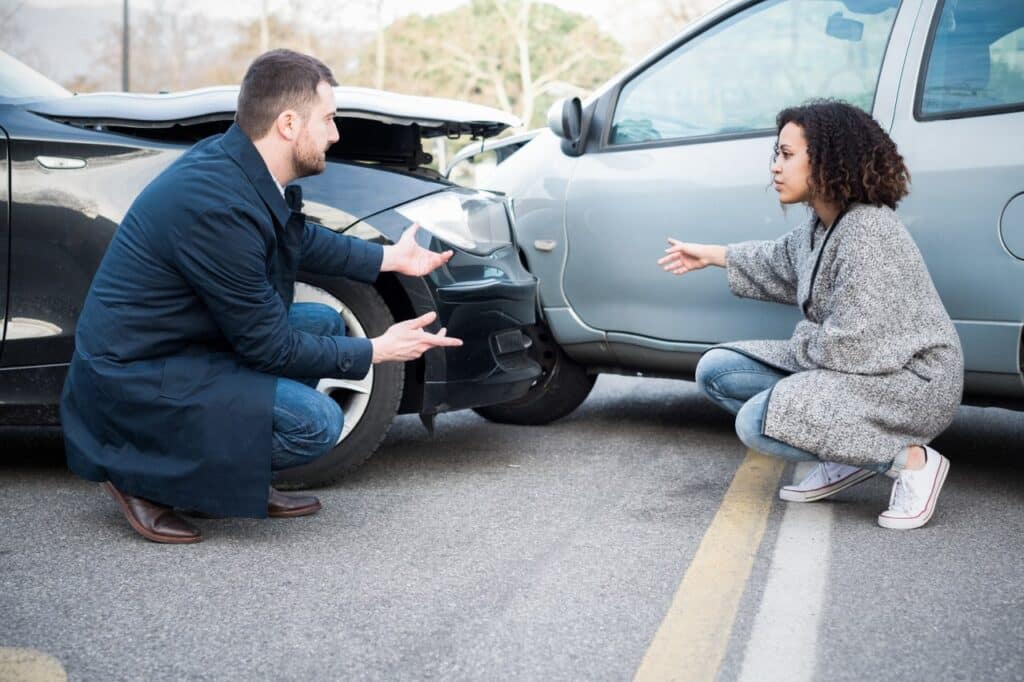 Car-Accident-Attorney-Brownsville-TX Two people discuss a minor car accident, examining the damage on their vehicles on a road. | Sky Rye Design Two people discuss a minor car accident, examining the damage on their vehicles on a road.
