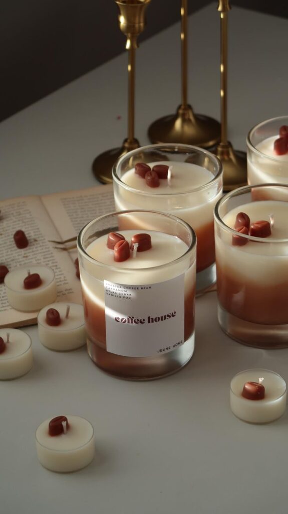 Elegant coffee-scented candles in glass jars with decorative accents, set on a table, casting a warm ambiance for relaxation.