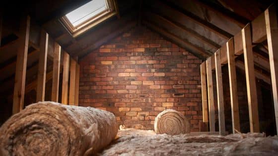 Common Causes of Heat Loss in Lofts and How Proper Insulation Solves Them Attic being insulated with rolls of fiberglass insulation, brick wall and skylight visible, highlighting energy efficiency and home improvement. | Sky Rye Design Attic being insulated with rolls of fiberglass insulation, brick wall and skylight visible, highlighting energy efficiency and home improvement.
