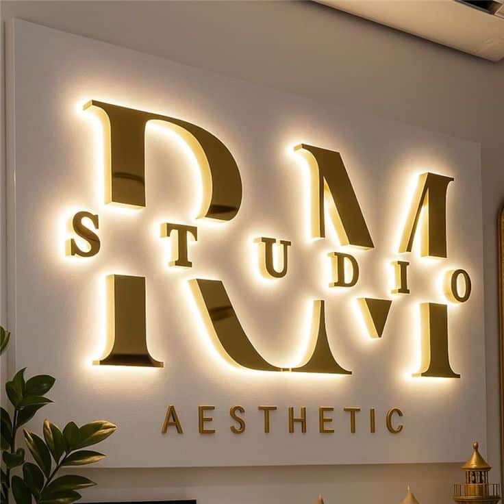Custom 3D Stainless Steel LED Business Sign Illuminated Metal Logo Letters Outdoor Office Store Illuminated RM Studio Aesthetic sign on wall, featuring gold letters with decorative plants below, creating a modern, stylish look. | Sky Rye Design Illuminated RM Studio Aesthetic sign on wall, featuring gold letters with decorative plants below, creating a modern, stylish look.