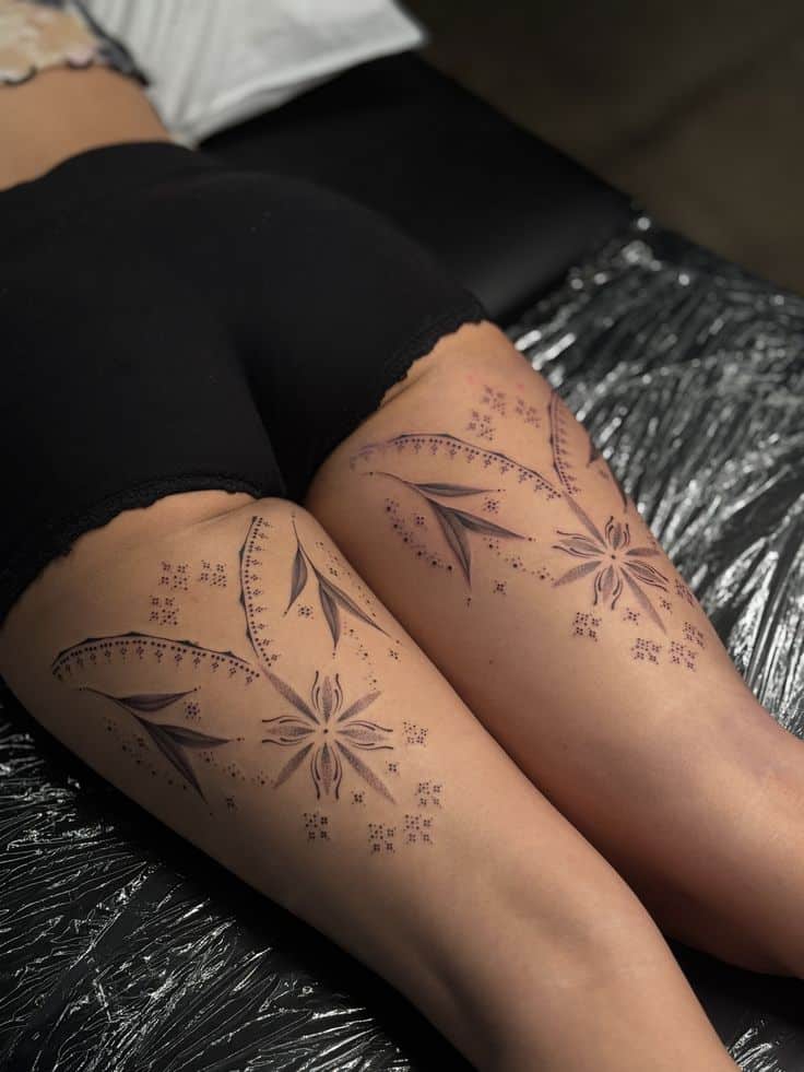 Cute rnamental thigh tattoos Floral thigh tattoos with intricate leaf patterns, designed on both legs, showcasing artistic body art in a tattoo studio setting. | Sky Rye Design Floral thigh tattoos with intricate leaf patterns, designed on both legs, showcasing artistic body art in a tattoo studio setting.