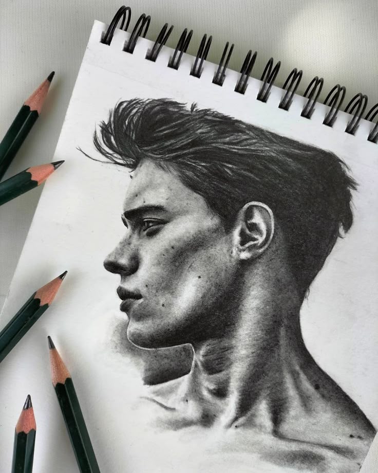 Dessin Pencil sketch of a man's profile on a notepad, surrounded by green pencils, showcasing artistic shading and detail. | Sky Rye Design Pencil sketch of a man's profile on a notepad, surrounded by green pencils, showcasing artistic shading and detail.