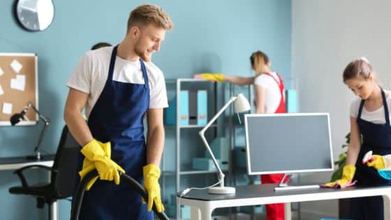 Essential Cleaning Services Every Should Use Office cleaning team at work: a man vacuums, while two women clean desks in a brightly lit modern office. | Sky Rye Design Office cleaning team at work: a man vacuums, while two women clean desks in a brightly lit modern office.