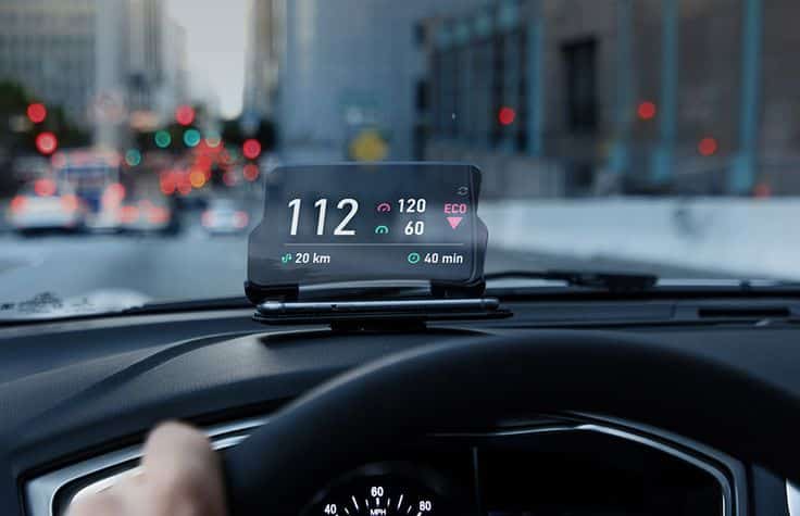 Car dashboard with a digital head-up display showing speed, eco mode, distance traveled, and driving time on a city street.