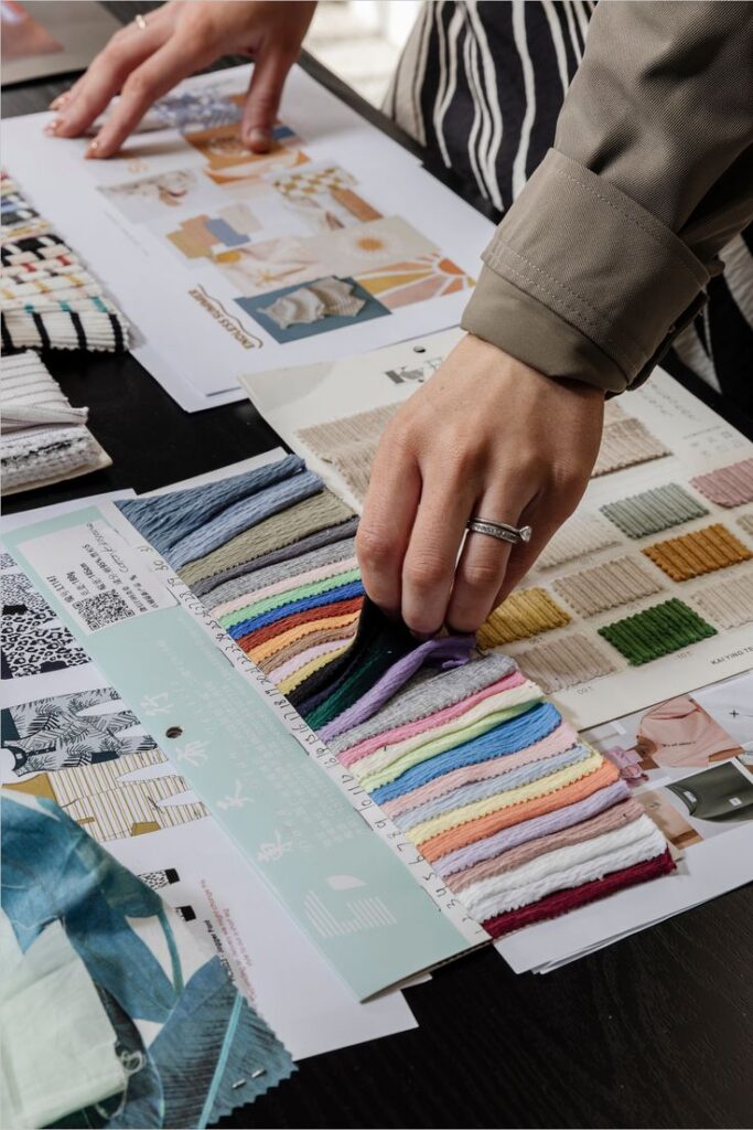 Fashion Fabric Swatches Designer selecting colorful fabric swatches and reading pattern catalogs for interior design project on a desk. | Sky Rye Design Designer selecting colorful fabric swatches and reading pattern catalogs for interior design project on a desk.