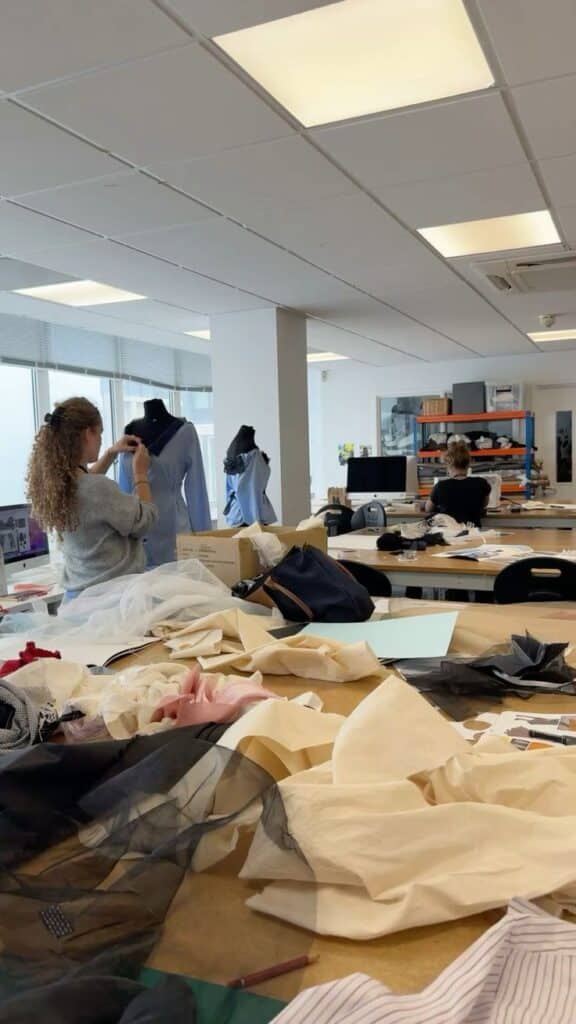 Fashion design Fashion design students working on dressmaking projects in a studio filled with fabrics, dress forms, and sewing materials. | Sky Rye Design Fashion design students working on dressmaking projects in a studio filled with fabrics, dress forms, and sewing materials.