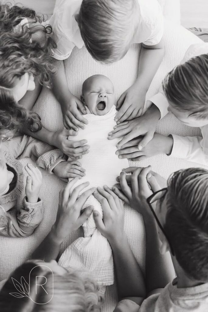 Five ways to turn your photography session into art - Reflections by Karen Byker Newborn baby surrounded by family hands, creating a loving circle of support and connection in a heartwarming black and white photo. | Sky Rye Design Newborn baby surrounded by family hands, creating a loving circle of support and connection in a heartwarming black and white photo.