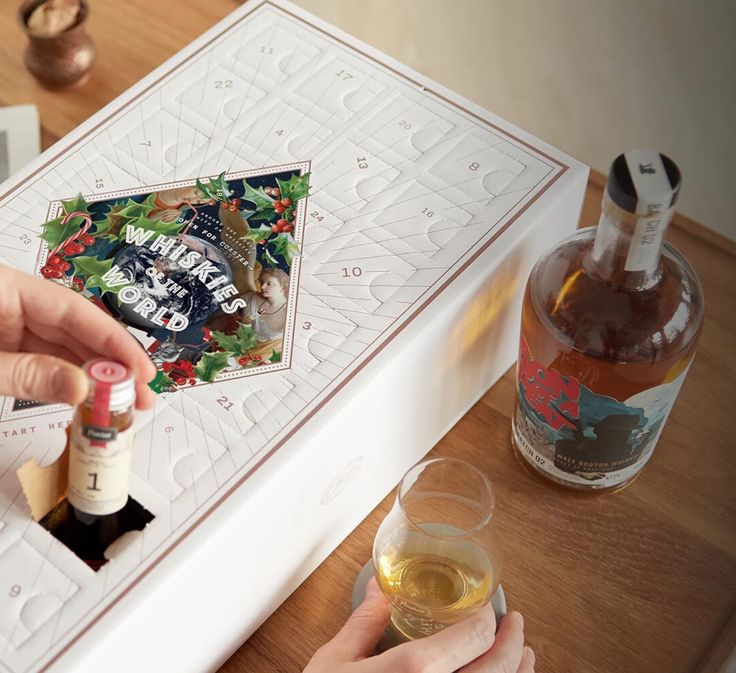 Advent calendar with Whiskies of the World theme, showing someone's hand holding a small bottle and another pouring a glass.