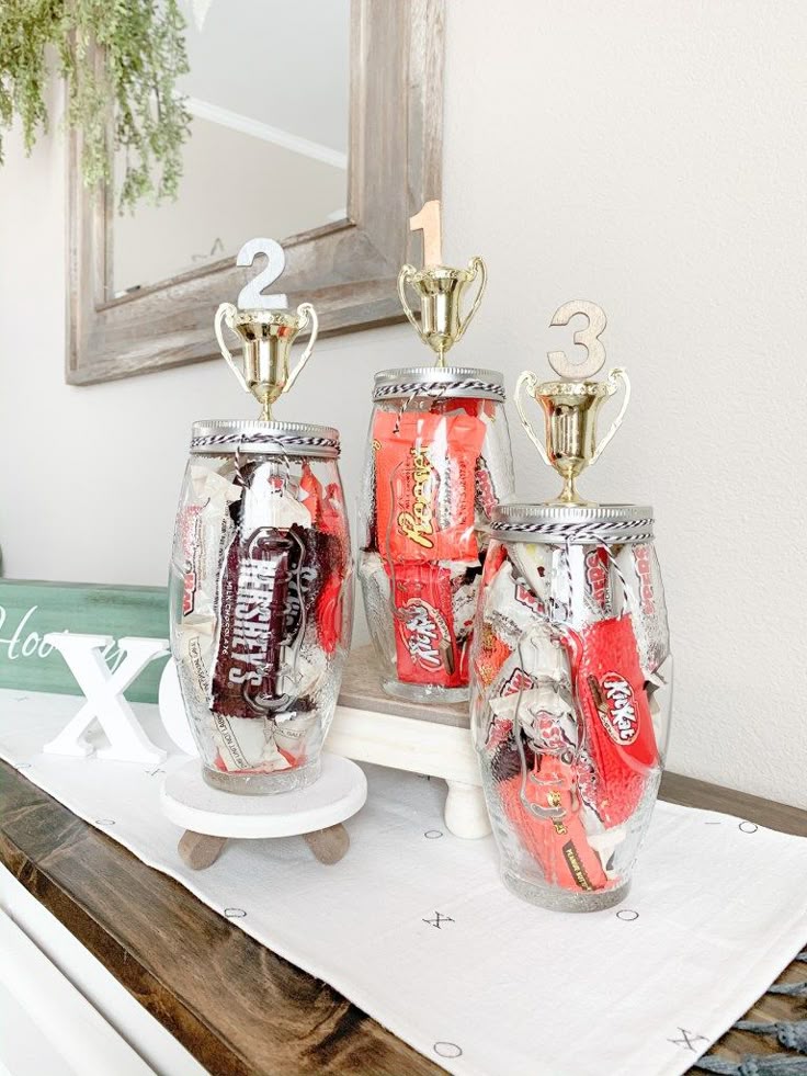Trophy jars filled with assorted chocolates, including Reese's and KitKats, creatively displayed as a decorative candy centerpiece.