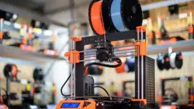 3D printer with filament spools in a workshop, showcasing modern additive manufacturing technology and equipment detail.