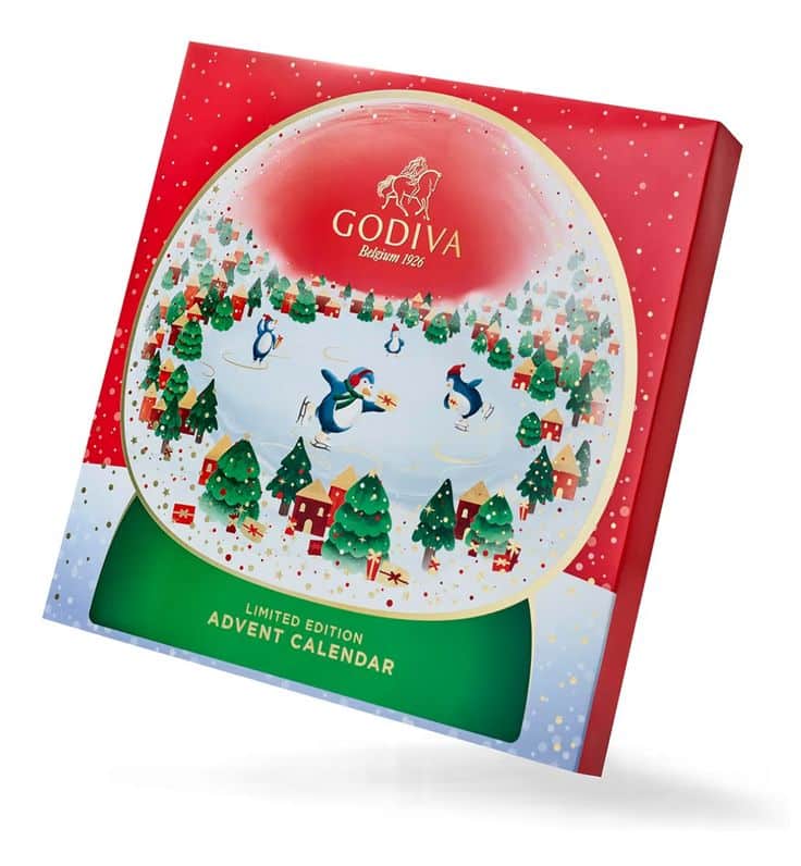 Limited edition Godiva advent calendar featuring a festive penguin design in a wintry scene, surrounded by trees and gifts.
