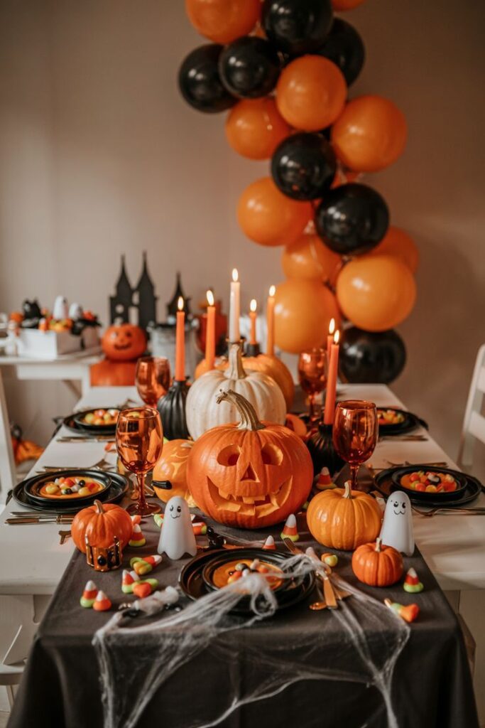 Halloween25 Festive Halloween table setting with carved pumpkins, orange and black balloons, candles, and candy corn for a spooky celebration. | Sky Rye Design Festive Halloween table setting with carved pumpkins, orange and black balloons, candles, and candy corn for a spooky celebration.