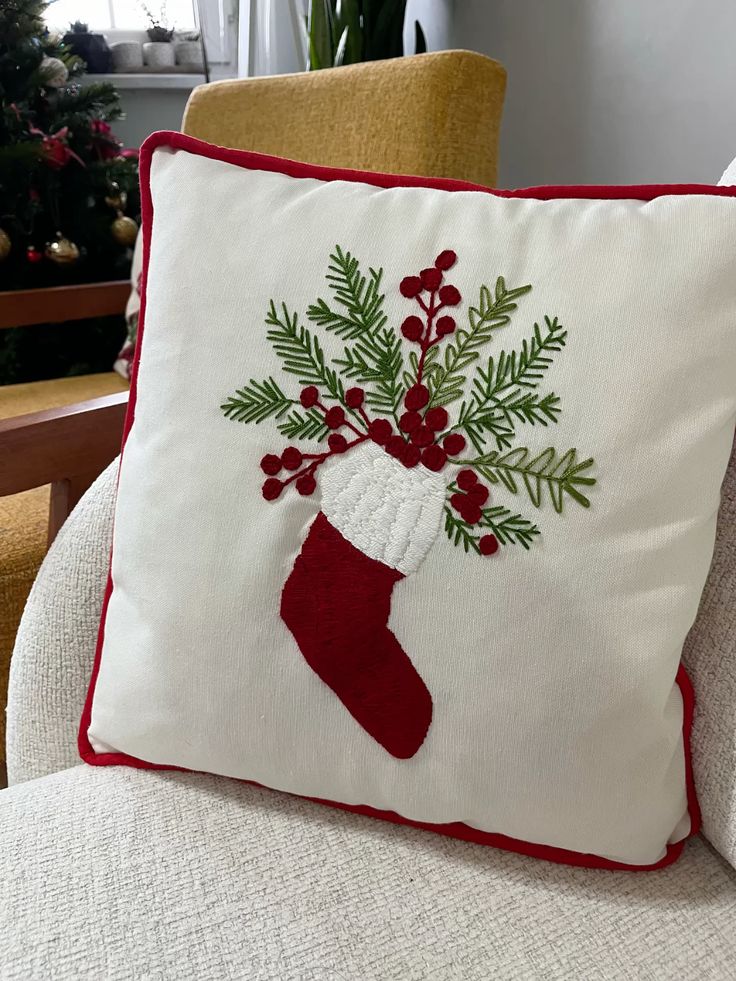 Hand-embroidered cushion cover for the New Year Festive holiday pillow with embroidered Christmas stocking and holly design, adding cozy decor to a living room with Christmas tree. | Sky Rye Design Festive holiday pillow with embroidered Christmas stocking and holly design, adding cozy decor to a living room with Christmas tree.