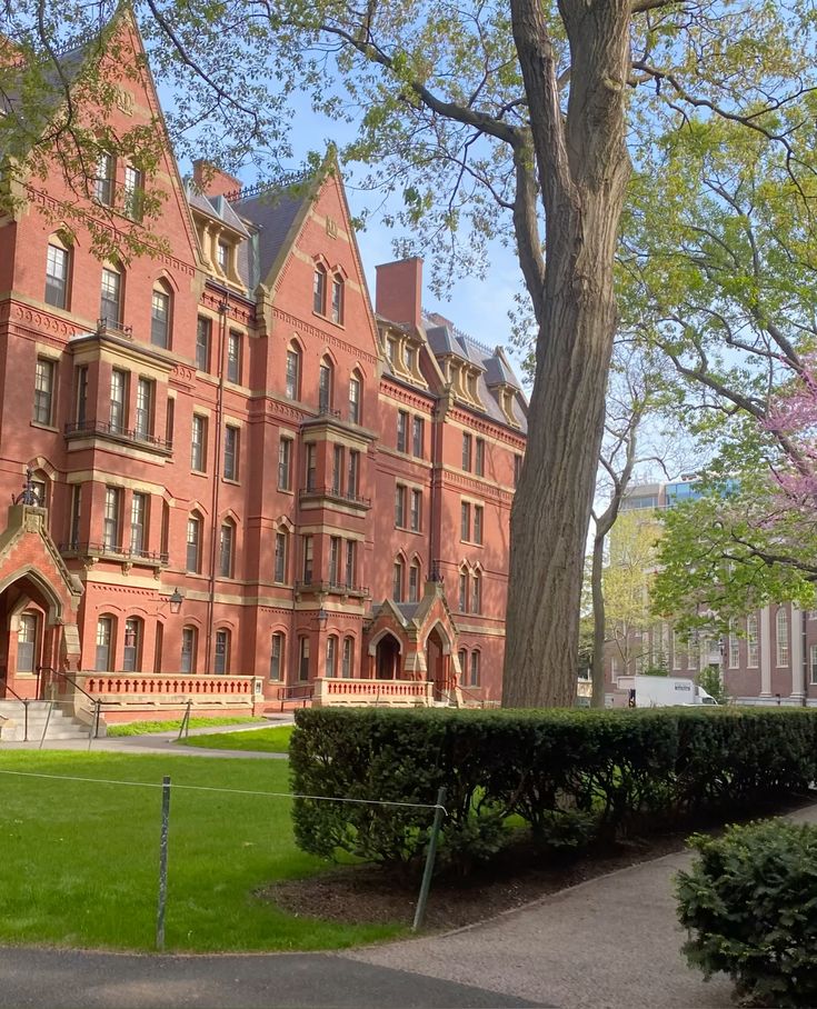 Harvard University Historic red-brick building with Gothic architecture surrounded by green lawns and trees under a clear blue sky. | Sky Rye Design Historic red-brick building with Gothic architecture surrounded by green lawns and trees under a clear blue sky.