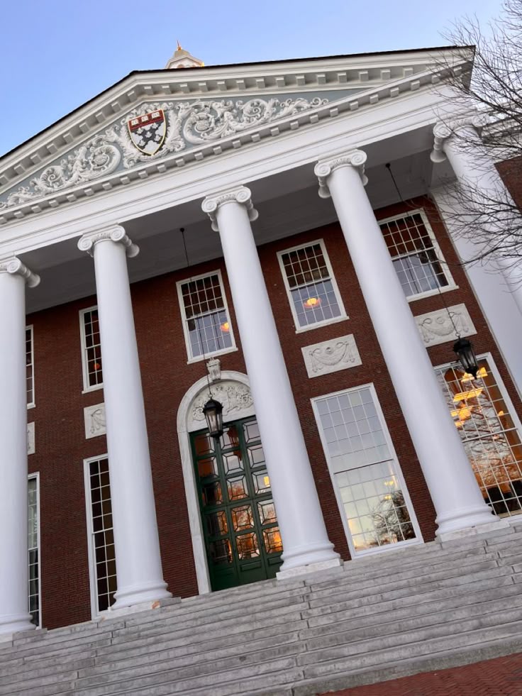 Harvard university_ Historic university building with grand columns and intricate pediment. Majestic entrance with steps leading up. Daytime view. | Sky Rye Design Historic university building with grand columns and intricate pediment. Majestic entrance with steps leading up. Daytime view.