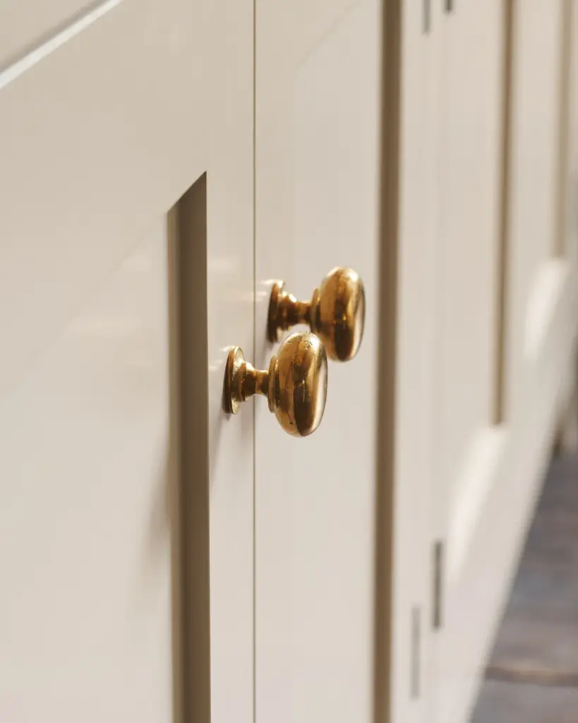 Close-up of elegant white cabinet doors with shiny gold knobs, highlighting modern kitchen design and stylish home decor.