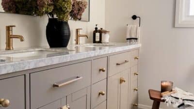 Elegant bathroom with double sink vanity, bronze fixtures, marble countertop, and decorative accents for a sophisticated, minimal design.