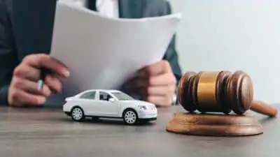Man examines documents near a gavel and car model, symbolizing legal proceedings or automobile law.