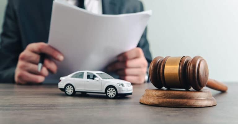 How Can a Car Accident Lawyer Help When Insurance Denies the Claim Man examines documents near a gavel and car model, symbolizing legal proceedings or automobile law. | Sky Rye Design Man examines documents near a gavel and car model, symbolizing legal proceedings or automobile law.