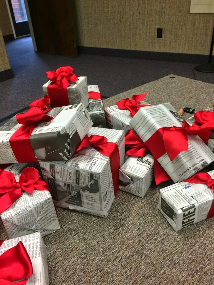 Gifts wrapped in newspaper with red ribbons, placed on a carpet, creating a unique and eco-friendly presentation for special occasions.