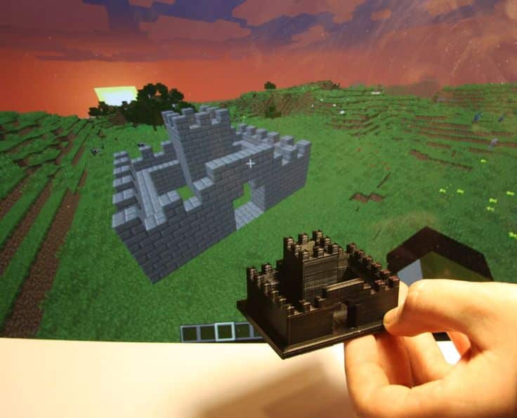 How to 3D Print Your Minecraft World Using Mineways 1 3D-printed castle model held in front of a computer screen displaying a similar Minecraft castle design in a scenic digital landscape. | Sky Rye Design 3D-printed castle model held in front of a computer screen displaying a similar Minecraft castle design in a scenic digital landscape.