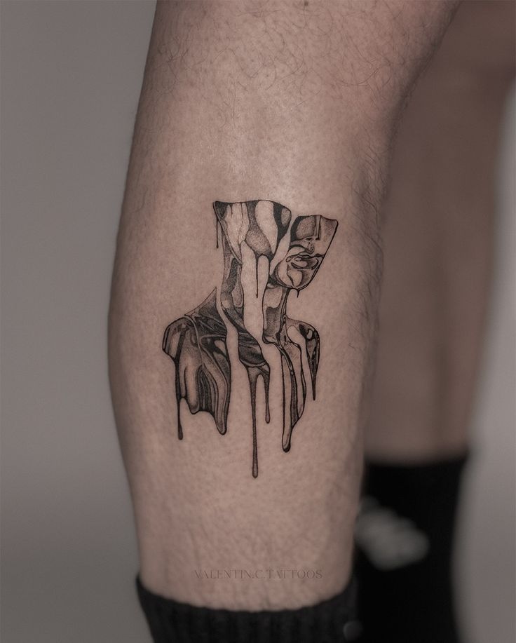 Dripping abstract face tattoo on leg, showcasing unique line art and shading. Perfect for artistic tattoo inspiration.