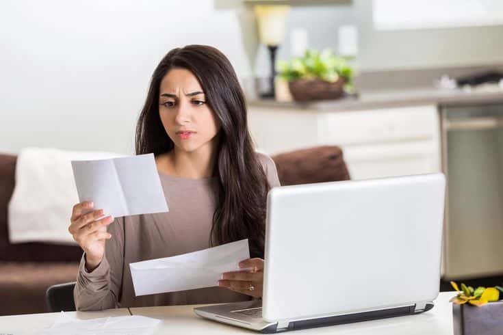 Insurance Articles Information_ Allstate Resources Woman concerned while reading documents at home, laptop open on table. Analyzing finances or bills in modern kitchen setting. | Sky Rye Design Woman concerned while reading documents at home, laptop open on table. Analyzing finances or bills in modern kitchen setting.
