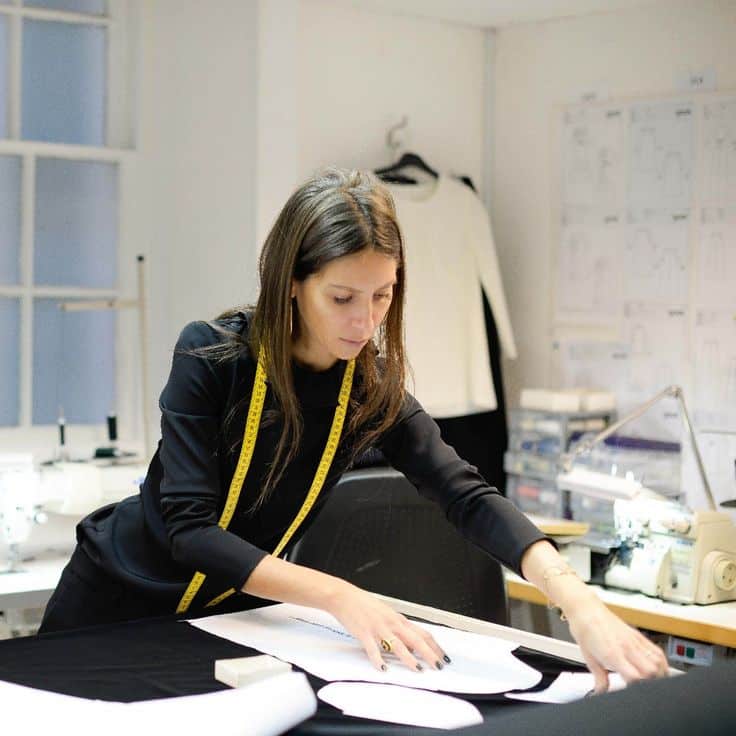 Jane _ The Jane Atelier Luxury Style Brand Story Fashion designer at work, using patterns and measuring tape in studio. Sewing equipment and sketches in the background. Creative process. | Sky Rye Design Fashion designer at work, using patterns and measuring tape in studio. Sewing equipment and sketches in the background. Creative process.