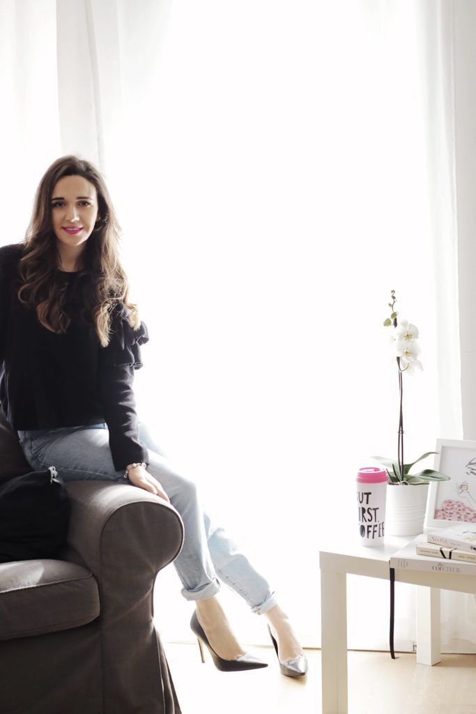 Key Skills for Starting a Fashion Business - GLAM OBSERVER Woman smiling on a sofa in bright room with coffee mug, books, and orchid on table. Cozy, relaxed atmosphere. | Sky Rye Design Woman smiling on a sofa in bright room with coffee mug, books, and orchid on table. Cozy, relaxed atmosphere.