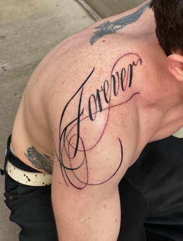 Lettering Man with Forever tattoo in elegant script on shoulder, showcasing bold ink art and self-expression. | Sky Rye Design Man with Forever tattoo in elegant script on shoulder, showcasing bold ink art and self-expression.