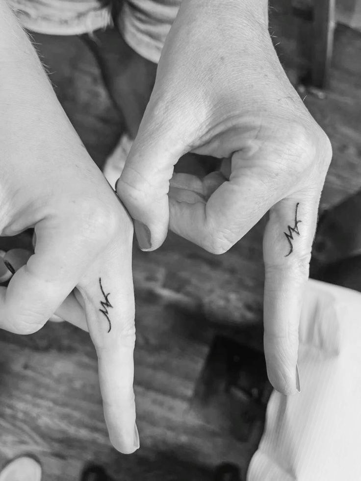 Matching initials finger tattoos Close-up of hands with matching heartbeat tattoos on the index fingers, symbolizing connection and shared meaning. Black and white. | Sky Rye Design Close-up of hands with matching heartbeat tattoos on the index fingers, symbolizing connection and shared meaning. Black and white.