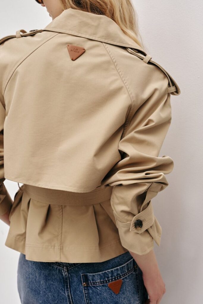 Mineral Cropped Trench - STONE _ 14 Tan trench coat with button detail, styled effortlessly over blue jeans. Trendy back view for casual fashion inspiration. | Sky Rye Design Tan trench coat with button detail, styled effortlessly over blue jeans. Trendy back view for casual fashion inspiration.