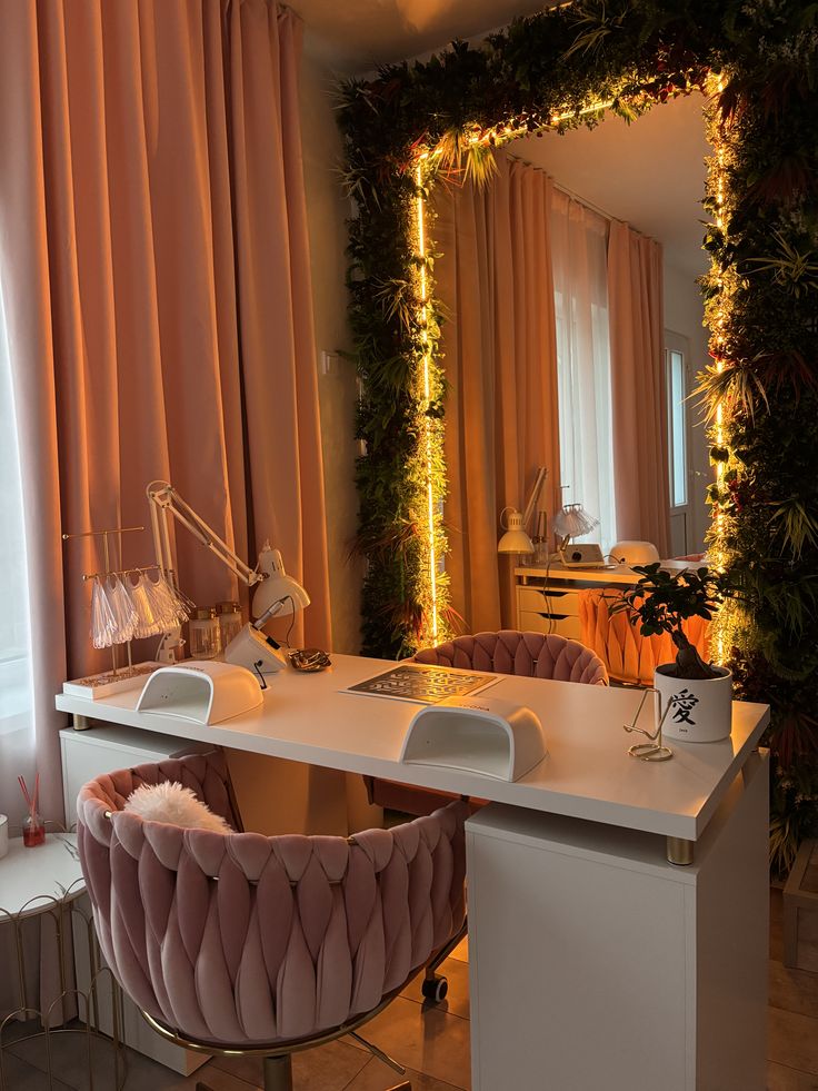 Stylish manicure salon with pink velvet chairs, white desk, and illuminated greenery, creating an inviting and luxurious atmosphere.