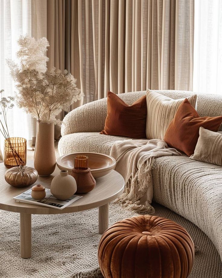 Neue Herbstdeko-Trends 2024_ 14 kreative Ideen Cozy living room with beige sectional sofa, rust-colored cushions, and a wooden coffee table featuring vases and dried flowers. | Sky Rye Design Cozy living room with beige sectional sofa, rust-colored cushions, and a wooden coffee table featuring vases and dried flowers.