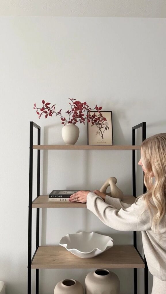 Neutral Bookshelf Styling Idea - Shop on LTK Modern living room shelf decor with red foliage in a vase, books, ceramic sculptures, and neutral tones for minimalist design inspiration. | Sky Rye Design Modern living room shelf decor with red foliage in a vase, books, ceramic sculptures, and neutral tones for minimalist design inspiration.