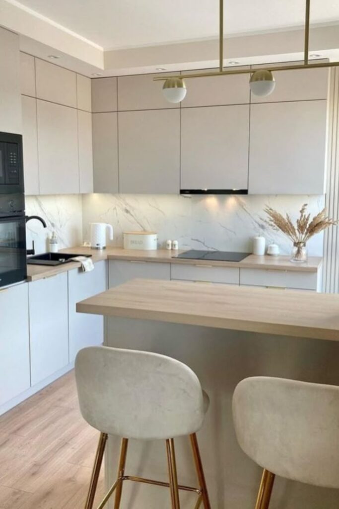 Neutral Kitchen Ideas Modern kitchen with beige cabinetry, marble backsplash, island bar, and elegant lighting. Cozy and minimalist design. | Sky Rye Design Modern kitchen with beige cabinetry, marble backsplash, island bar, and elegant lighting. Cozy and minimalist design.