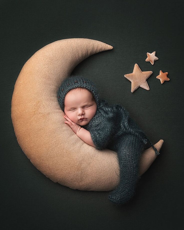 Newborn Portfolio Sleeping baby in a cozy outfit resting on a plush crescent moon with stars, creating a dreamy nighttime scene. | Sky Rye Design Sleeping baby in a cozy outfit resting on a plush crescent moon with stars, creating a dreamy nighttime scene.