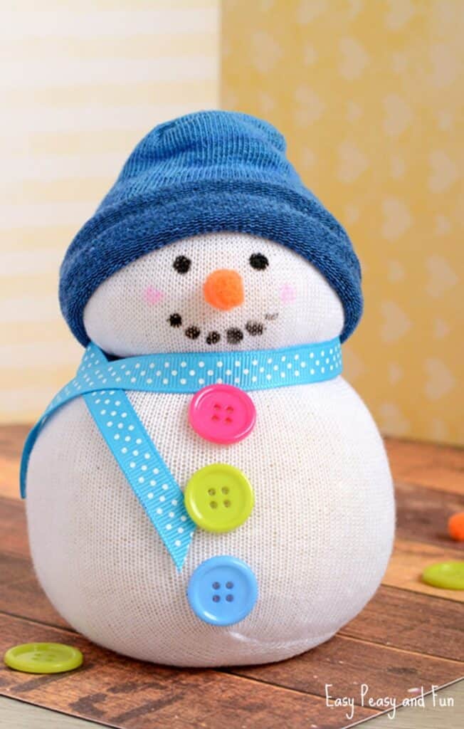 No-Sew-Sock-Snowman-Craft Adorable DIY sock snowman with blue hat, colorful buttons, and ribbon scarf. Perfect winter craft for kids and festive home decor. | Sky Rye Design Adorable DIY sock snowman with blue hat, colorful buttons, and ribbon scarf. Perfect winter craft for kids and festive home decor.
