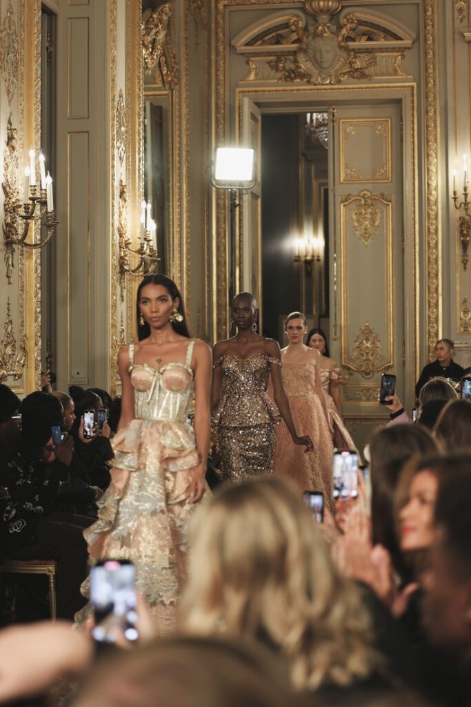 PARIS FASHION WEEK Models walking runway in elegant dresses during a luxurious fashion show in an ornate, gold-accented venue. | Sky Rye Design Models walking runway in elegant dresses during a luxurious fashion show in an ornate, gold-accented venue.