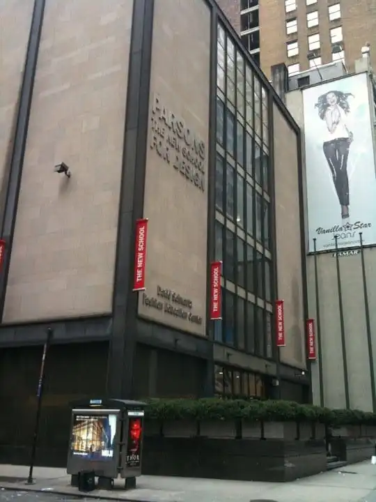 Exterior of Parsons The New School for Design building in New York City on a cloudy day, with a fashion billboard nearby.