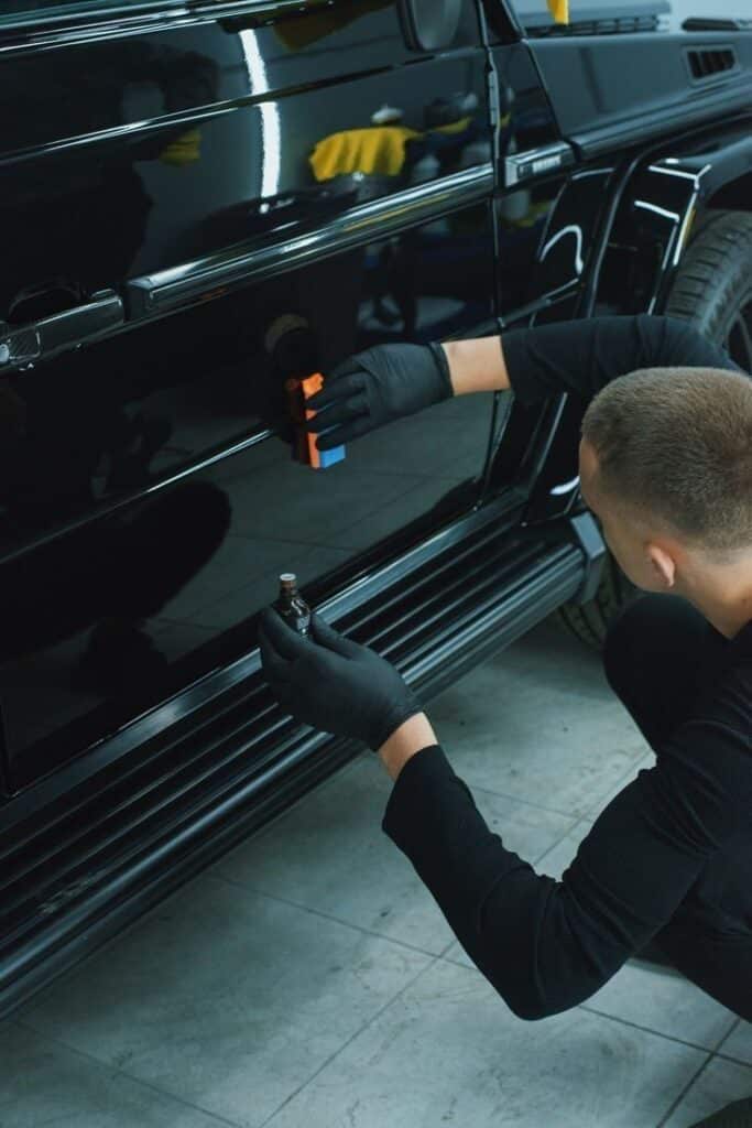 Perfect polishing Person applying ceramic coating to a black car, enhancing its shine and protection, with precision and care using specialized tools. | Sky Rye Design Person applying ceramic coating to a black car, enhancing its shine and protection, with precision and care using specialized tools.