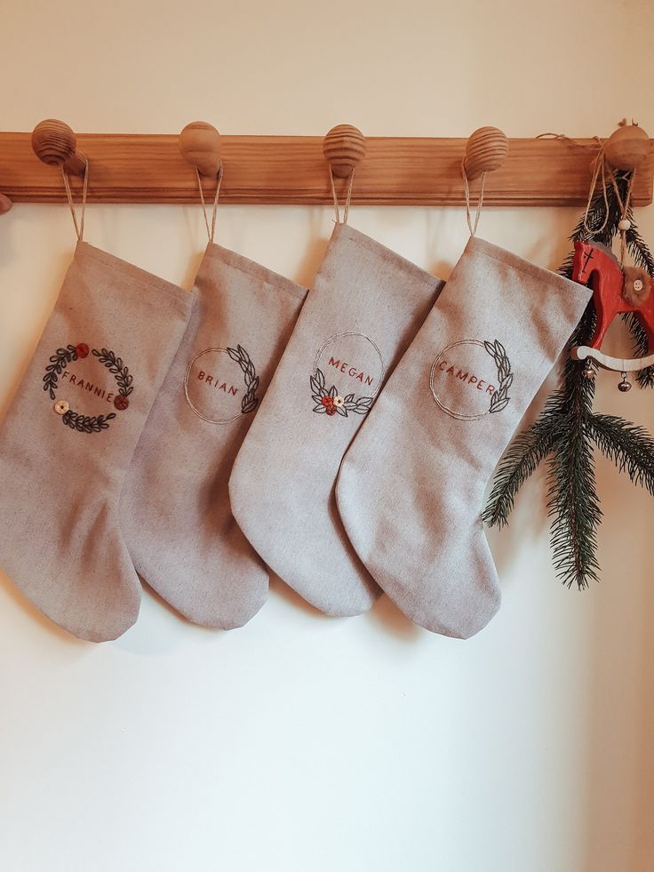 Personalized Family Christmas Santa stocking Custom name Christmas stocking Cotton Linen hand embroidered stockingKids Christmas stocking Four personalized Christmas stockings hang on wooden hooks, decorated with festive greenery and ornaments. | Sky Rye Design Four personalized Christmas stockings hang on wooden hooks, decorated with festive greenery and ornaments.
