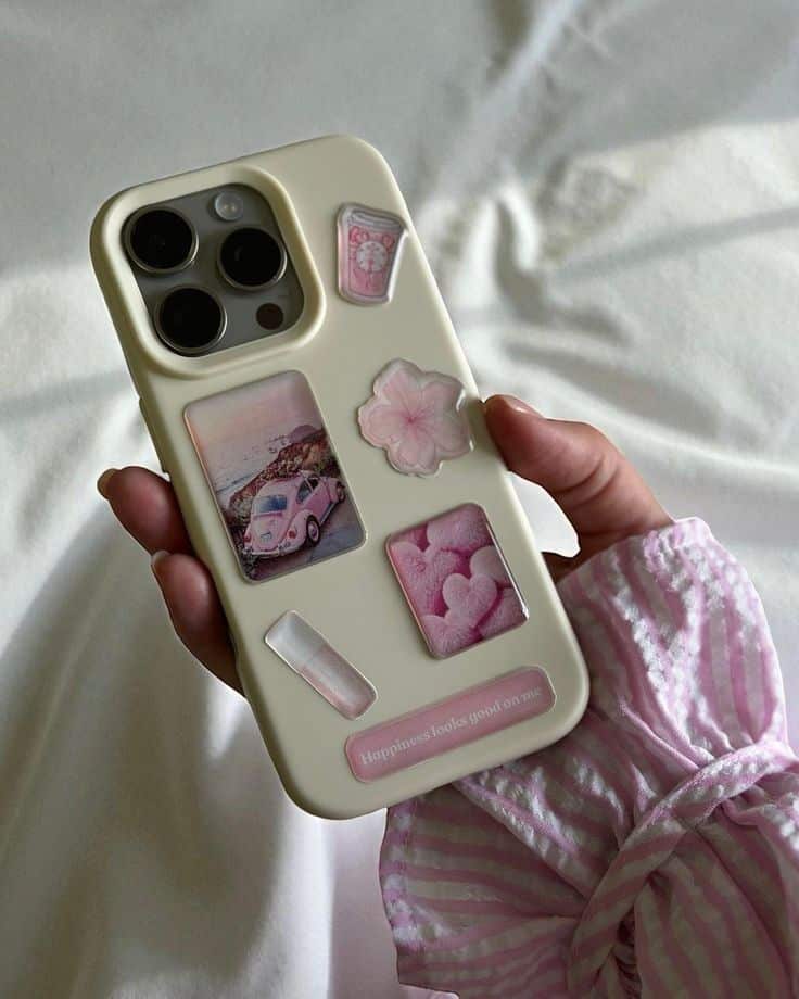 Pink Aesthetic Sticker Pack - Cute 3D Glossy Stickers for iPhone Case iPad MacBook Journal - Trendy Gift for Girls Hand holding a phone with a cream case featuring various pink stickers, including a car, flower, and hearts. | Sky Rye Design Hand holding a phone with a cream case featuring various pink stickers, including a car, flower, and hearts.