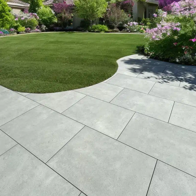 PisaGreyOutdoorPorcelainPavingSlabs-900x600x20mmvvb Modern patio with gray stone tiles next to a lush green lawn, surrounded by vibrant pink and purple flowers. Perfect outdoor space concept. | Sky Rye Design Modern patio with gray stone tiles next to a lush green lawn, surrounded by vibrant pink and purple flowers. Perfect outdoor space concept.