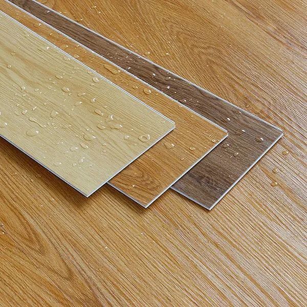 Variety of waterproof laminate flooring samples in light, medium, and dark wood textures with water droplets, ideal for home interiors.